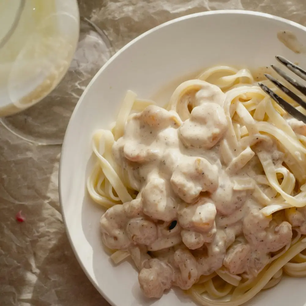 Creamy Alfredo sauce drizzled over pasta, with a sprinkle of Parmesan cheese and fresh herbs.