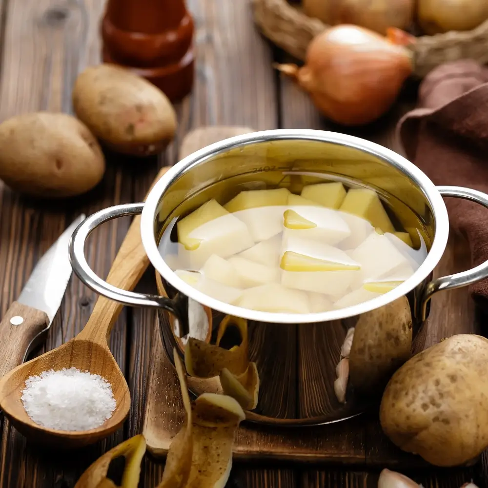 A pot of water boiling on a stovetop with fresh vegetables and pasta ready to cook, showcasing the boiling method.