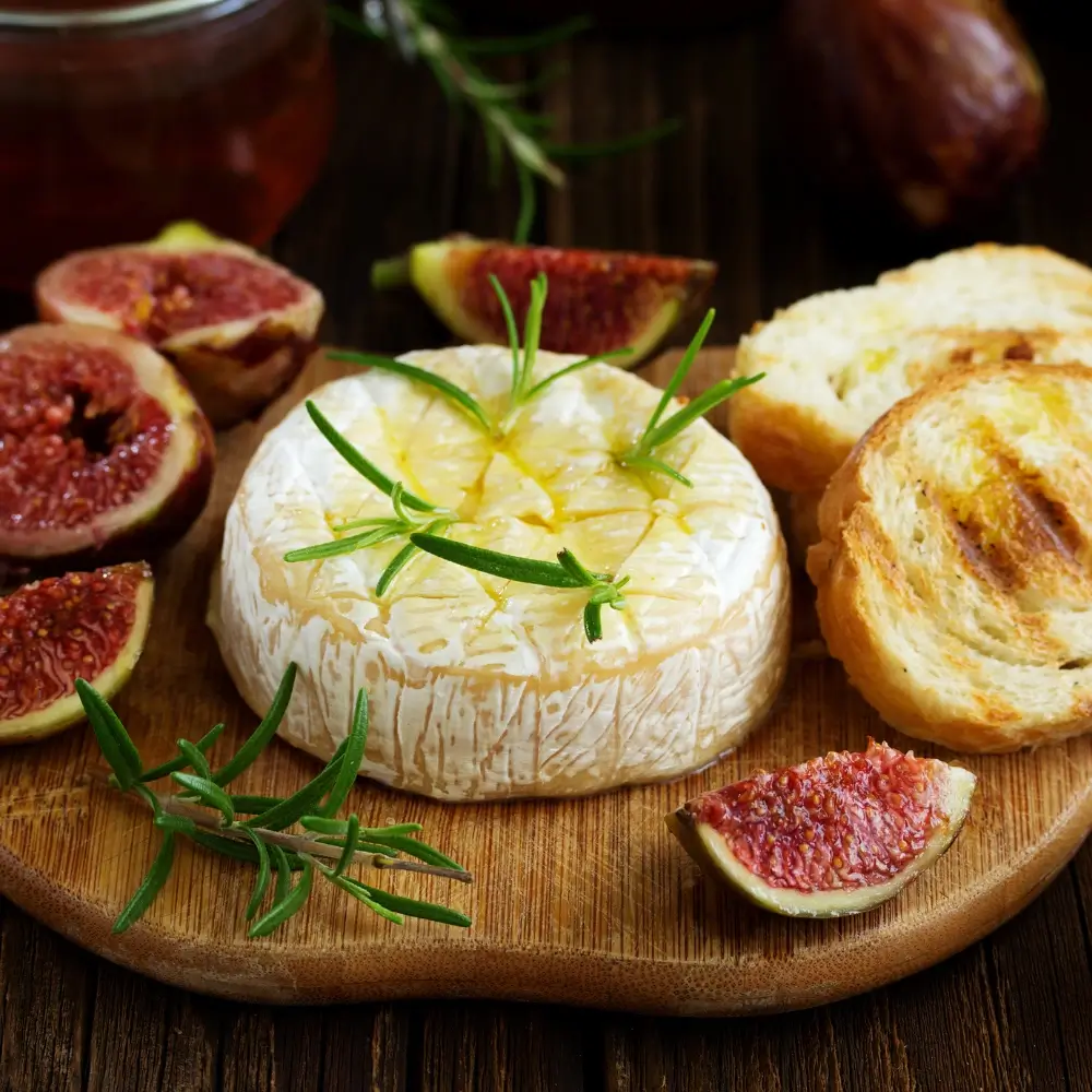 brie cheese bites: A slice of toasted bread topped with creamy brie cheese and sweet fruit jam, garnished with fresh herbs.