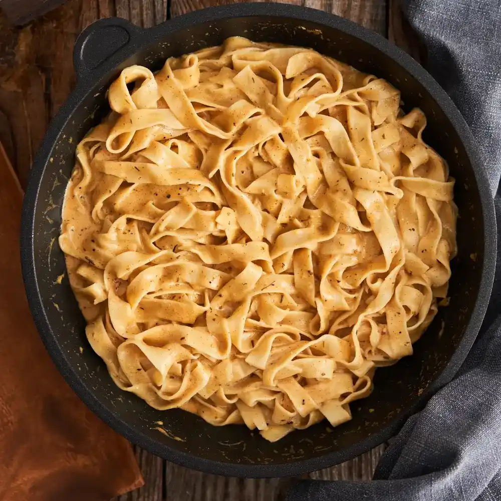 A creamy Cajun fettuccine Alfredo sauce, rich and spicy, coating perfectly cooked fettuccine pasta.