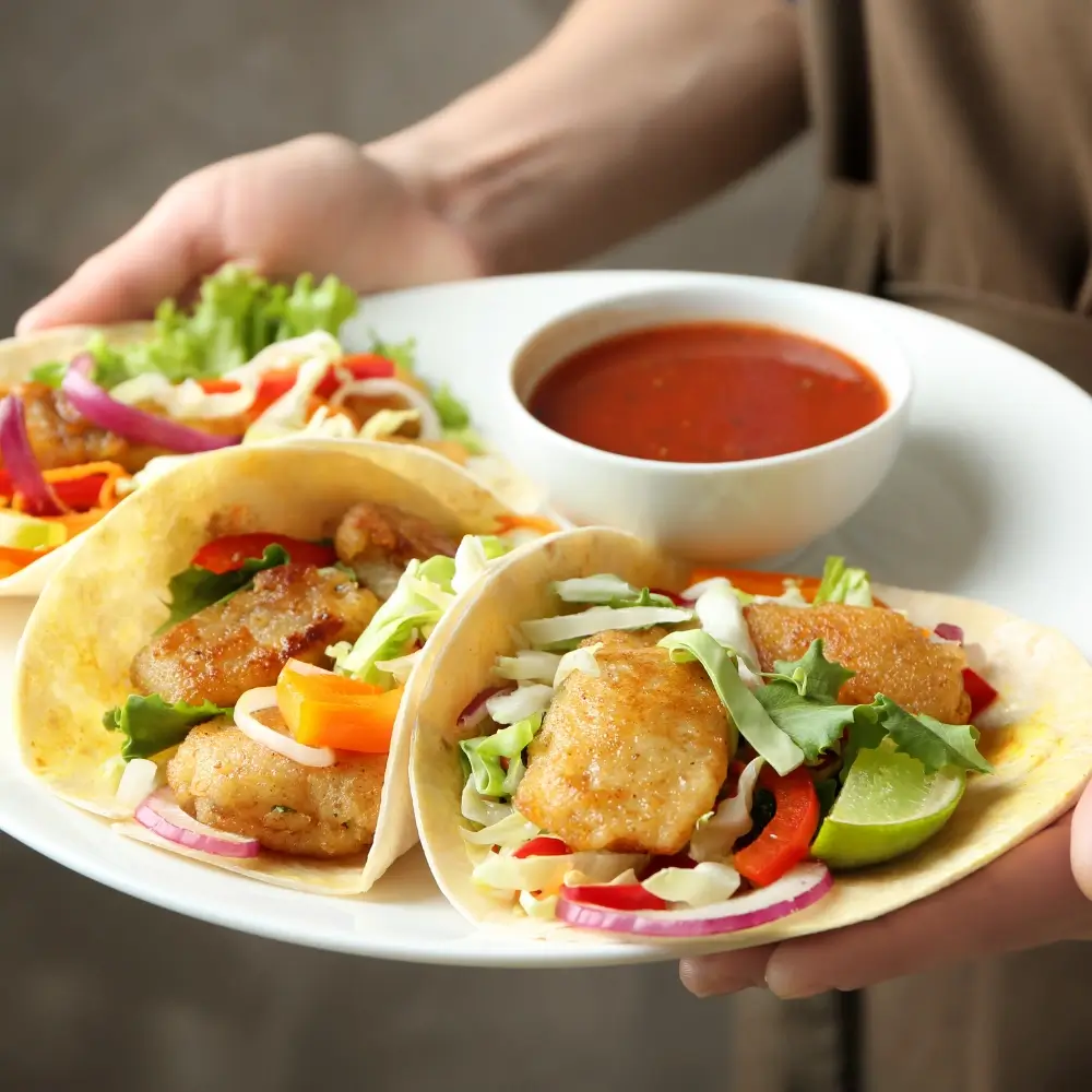 Fish Tacos served in soft tortillas, topped with fresh cabbage, creamy sauce, and a squeeze of lime.