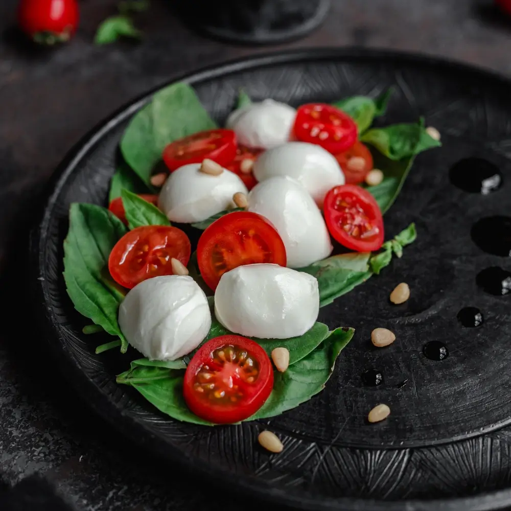 A vibrant Caprese salad with ripe tomatoes, fresh mozzarella, basil leaves, drizzled with olive oil and balsamic glaze.