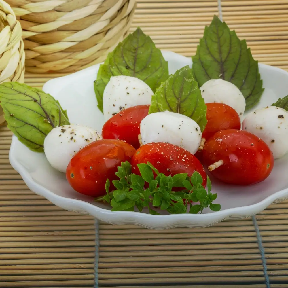 A vibrant Caprese salad with ripe tomatoes, fresh mozzarella, basil leaves, drizzled with olive oil and balsamic glaze.