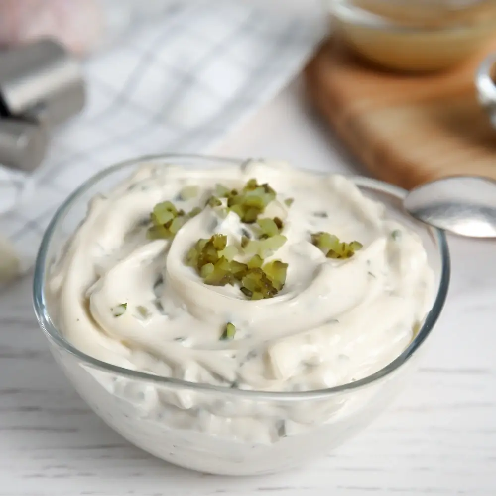 A bowl of creamy homemade tartar sauce, featuring chopped pickles, fresh herbs, and a tangy, flavorful base.