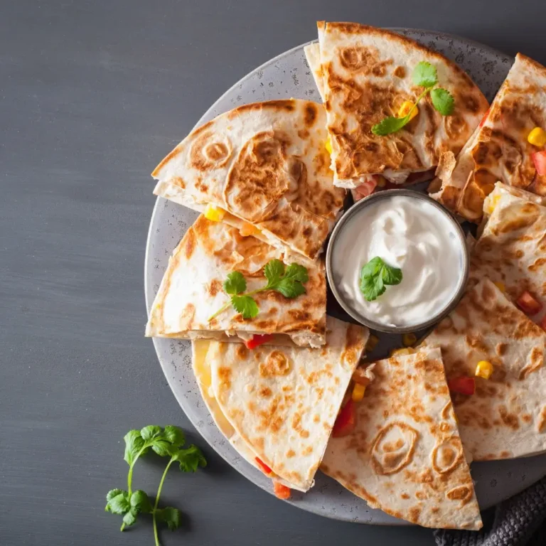 A plate of golden-brown chicken quesadillas, crispy on the outside and filled with melted cheese, grilled chicken, and vegetables.