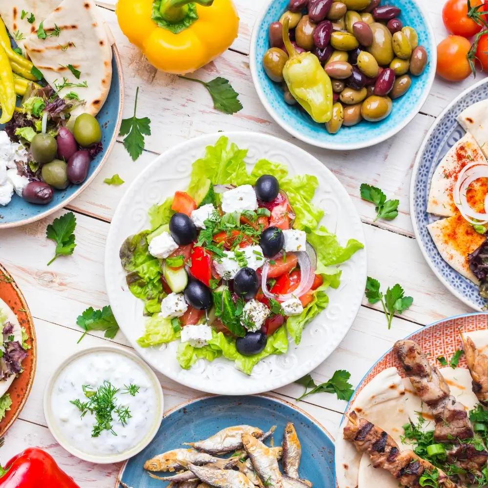 A colorful Greek salad with fresh vegetables, olives, feta cheese, and a drizzle of olive oil and herbs.