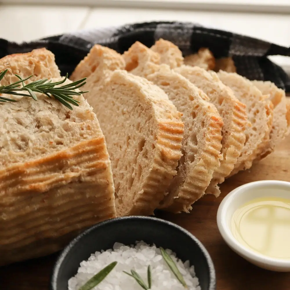 A freshly baked sourdough bread loaf with a golden crust, slightly cracked, showcasing its soft, airy interior.