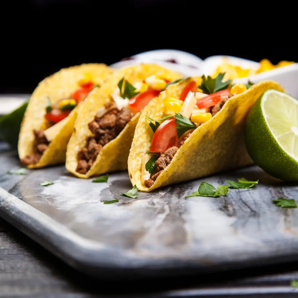 A plate of mouthwatering beef tacos, filled with seasoned ground beef, fresh toppings, and a soft tortilla shell.