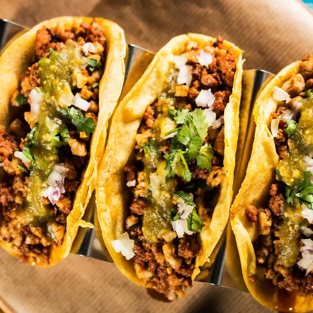 A plate of mouthwatering beef tacos, filled with seasoned ground beef, fresh toppings, and a soft tortilla shell.