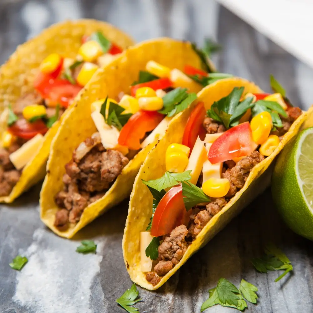 A plate of mouthwatering beef tacos, filled with seasoned ground beef, fresh toppings, and a soft tortilla shell.