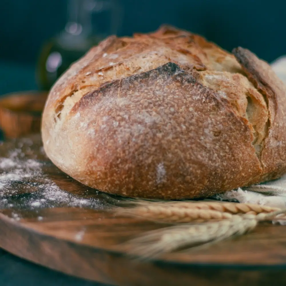 A freshly baked sourdough bread loaf with a golden crust, slightly cracked, showcasing its soft, airy interior.