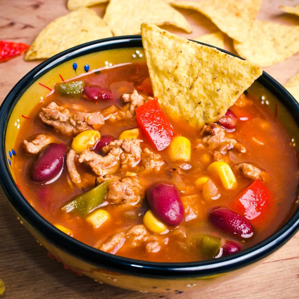 A taco soup recipe, loaded with hearty vegetables, beans and a flavorful broth, topped with crispy fried tortilla strips.