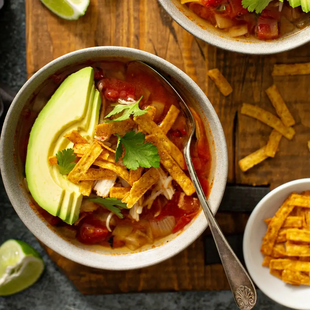 A taco soup recipe, loaded with hearty vegetables, beans and a flavorful broth, topped with crispy fried tortilla strips.