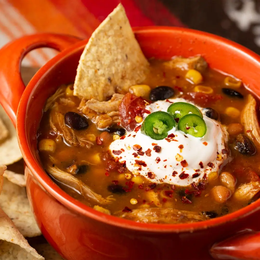 A taco soup recipe, loaded with hearty vegetables, beans and a flavorful broth, topped with crispy fried tortilla strips.